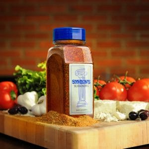 Seasoning spice blend on wooden cutting board with tomatoes, garlic, and cheese, Symeon's Greek Restaurant ingredient display.